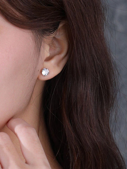Close-up of a person wearing a diamond stud earring with a neutral background
