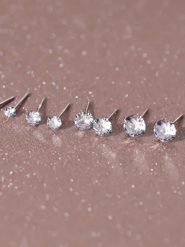 Set of silver stud earrings on a glittery brown surface