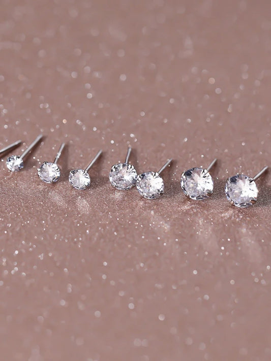 Set of silver stud earrings on a glittery brown surface