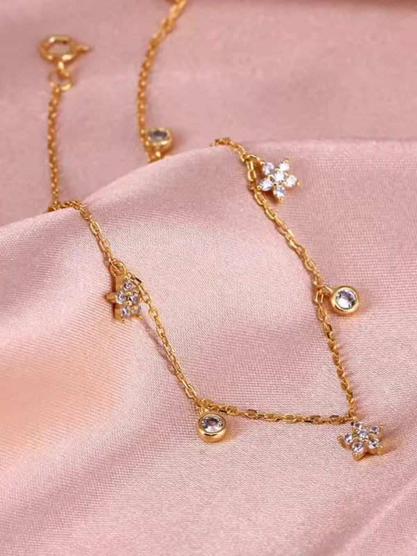 Gold bracelet with diamond-like stones on a pink fabric background