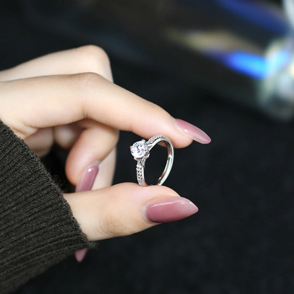 Hand holding a silver ring with a diamond on a blurred background