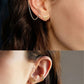Close-up of an ear wearing gold earrings with a blurred background