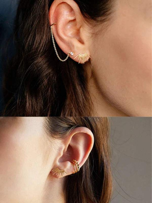Close-up of an ear wearing gold earrings with a blurred background