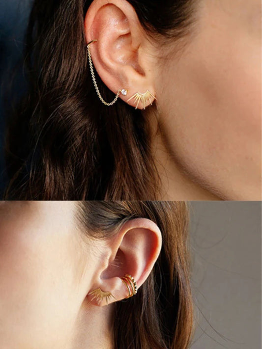 Close-up of an ear wearing gold earrings with a blurred background