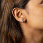 Close-up of an ear wearing a turquoise stud earring with a blurred background