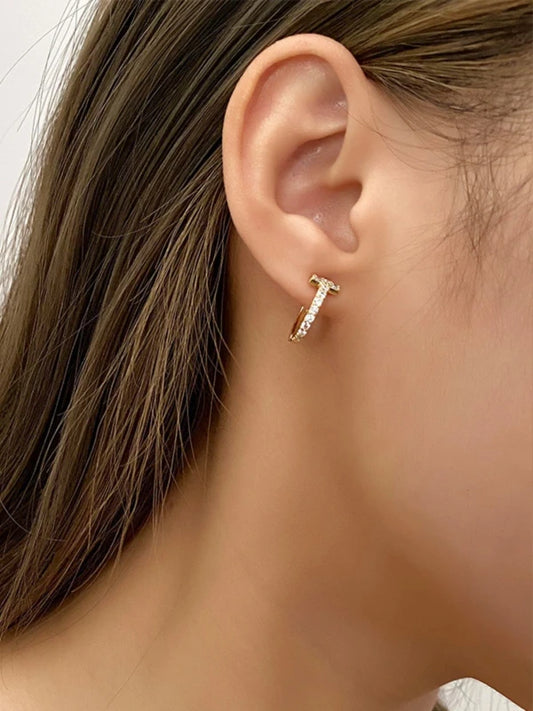 Close-up of an ear wearing a gold earring with a diamond.