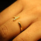 Gold ring and gold earring on a hand against a dark background