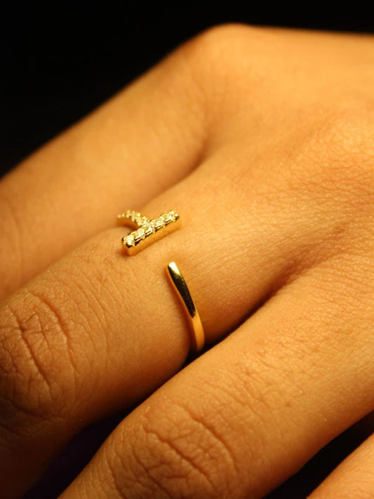 Gold ring and gold earring on a hand against a dark background