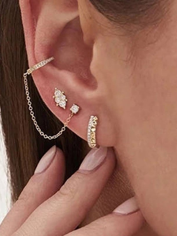 Close-up of an ear with gold earrings and a chain accessory.