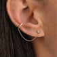 Gold ear cuff with a diamond on an ear against a blurred background