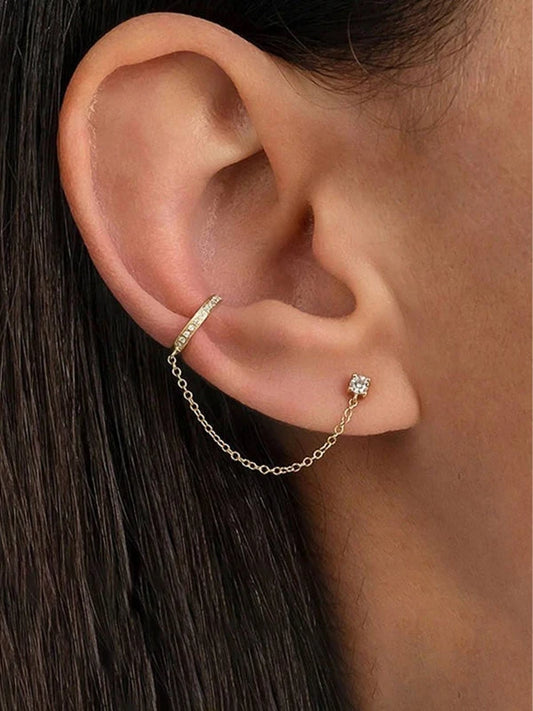 Gold ear cuff with a diamond on an ear against a blurred background
