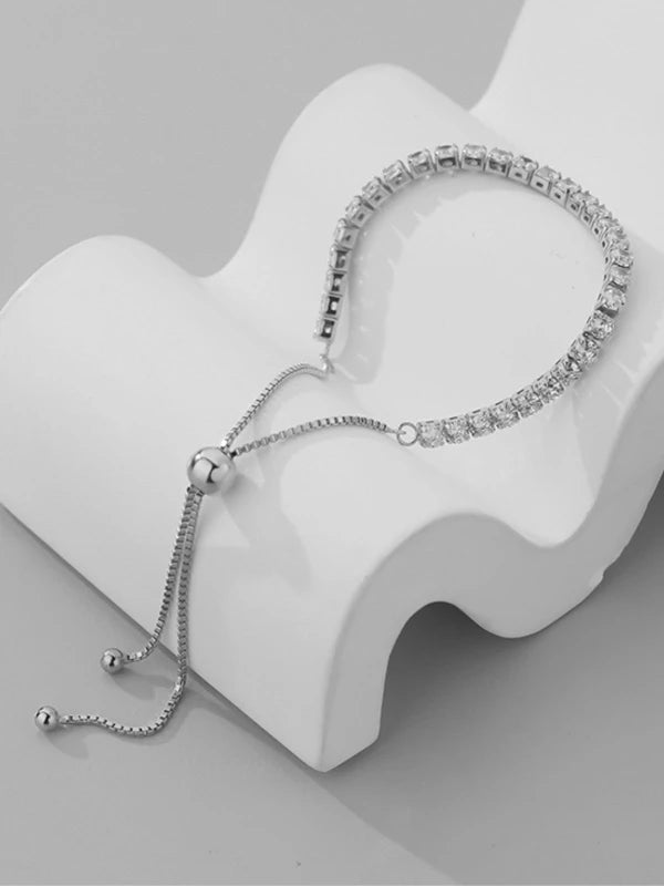 Silver bracelet with clear stones on a white jewelry stand