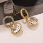 Gold earrings with clear gemstones on a neutral background