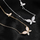 Three butterfly-shaped necklaces on a black fabric background